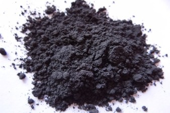 A pile of charcoal-coloured graphite power on a white surface.