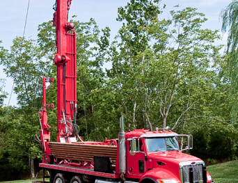 a large red and white truck is parked on a lush green field