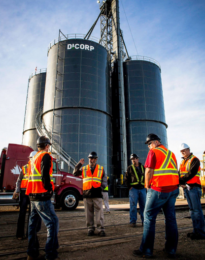 men standing next to four large silos