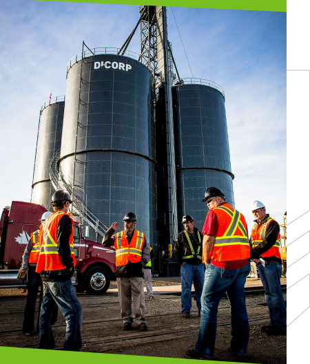 men standing next to four large silos