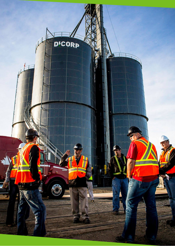 group of workers standing in front of four large silos